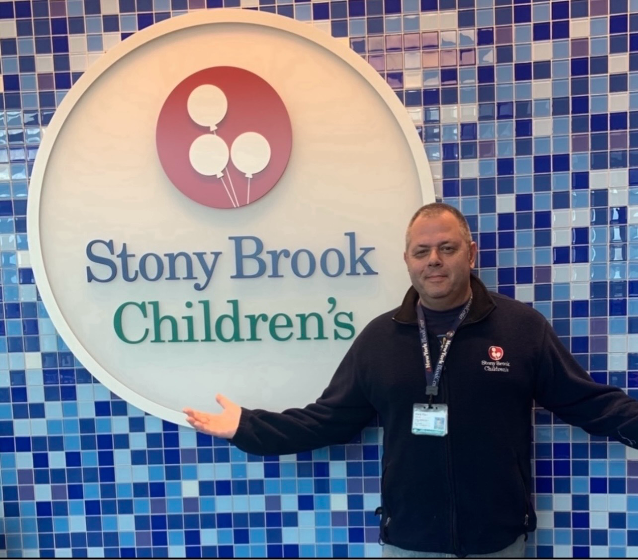 Man posing in front of Stony Brook Children's sign